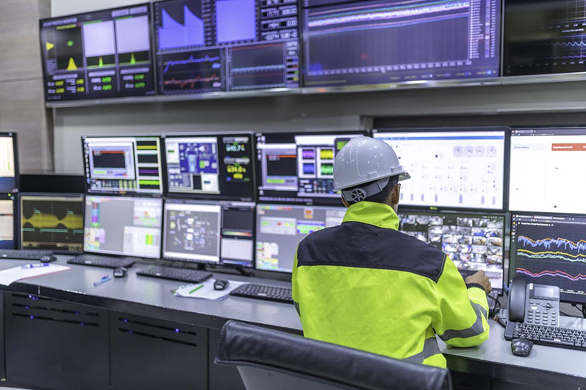 Operator monitoring live energy and metering data across a wall of control-room screens